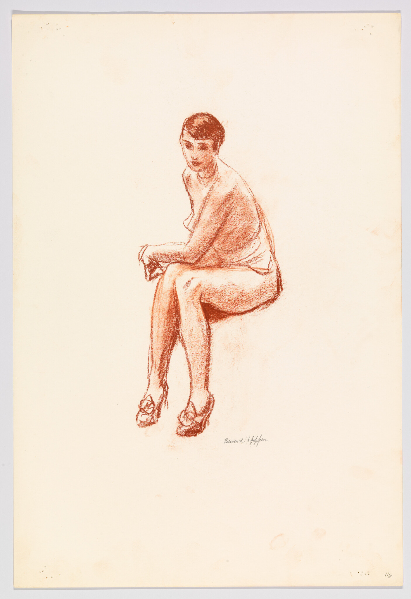 Seated woman with short hair sitting with hands clasped and legs crossed at knees.