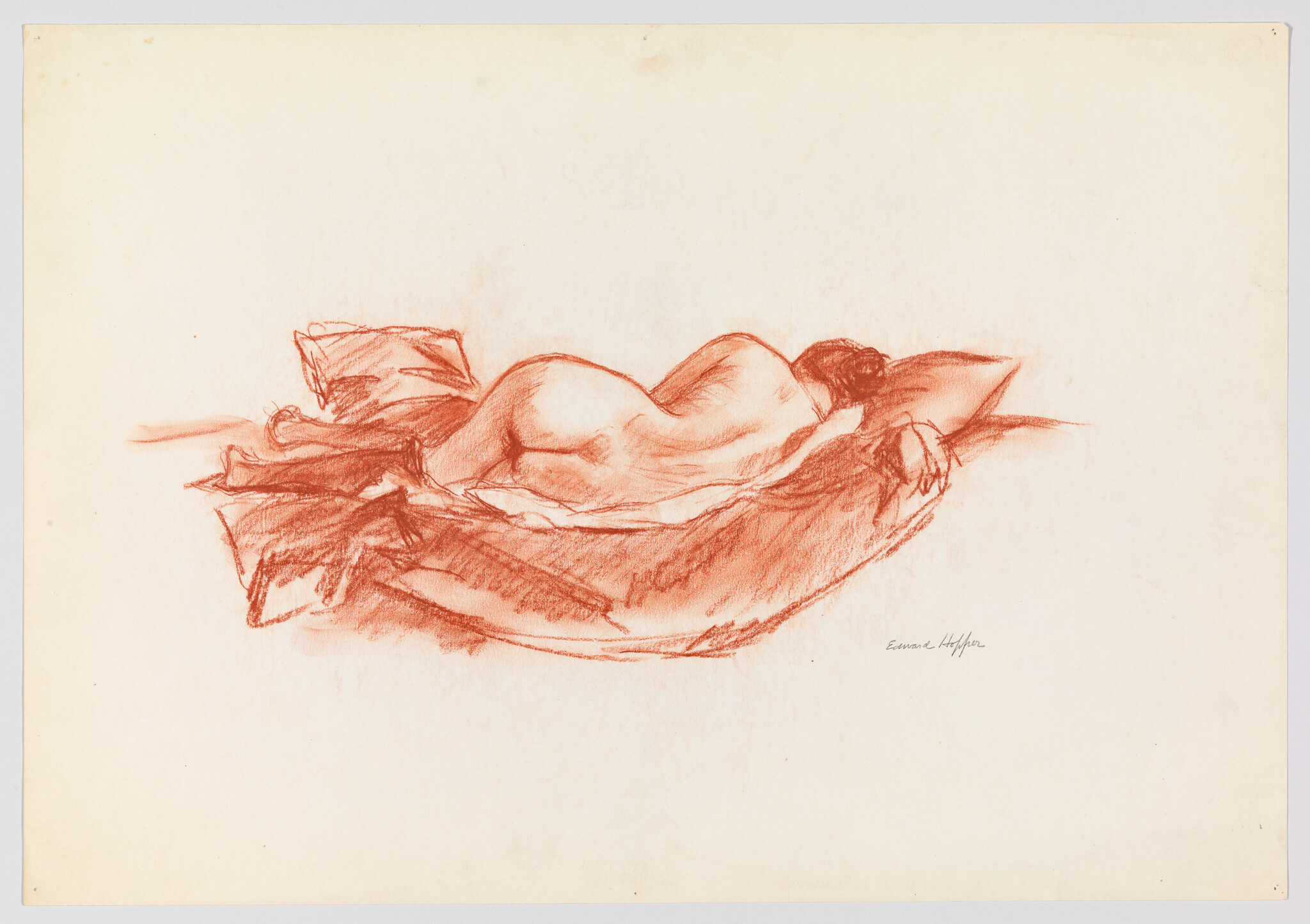 A reclining nude woman resting face down on pillows and soft blankets.