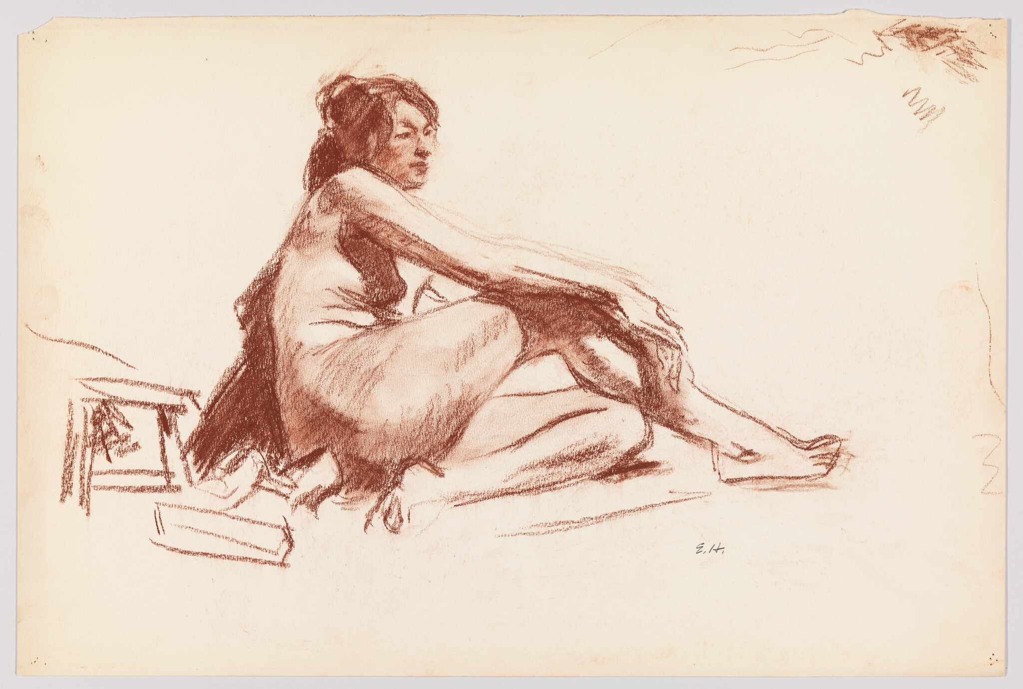 A seated woman in a loose dress leans forward with arms wrapped around her legs.