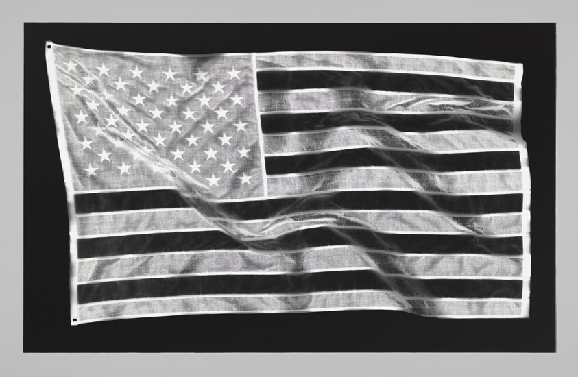 An American flag with stars and stripes hangs rippled against a dark background.