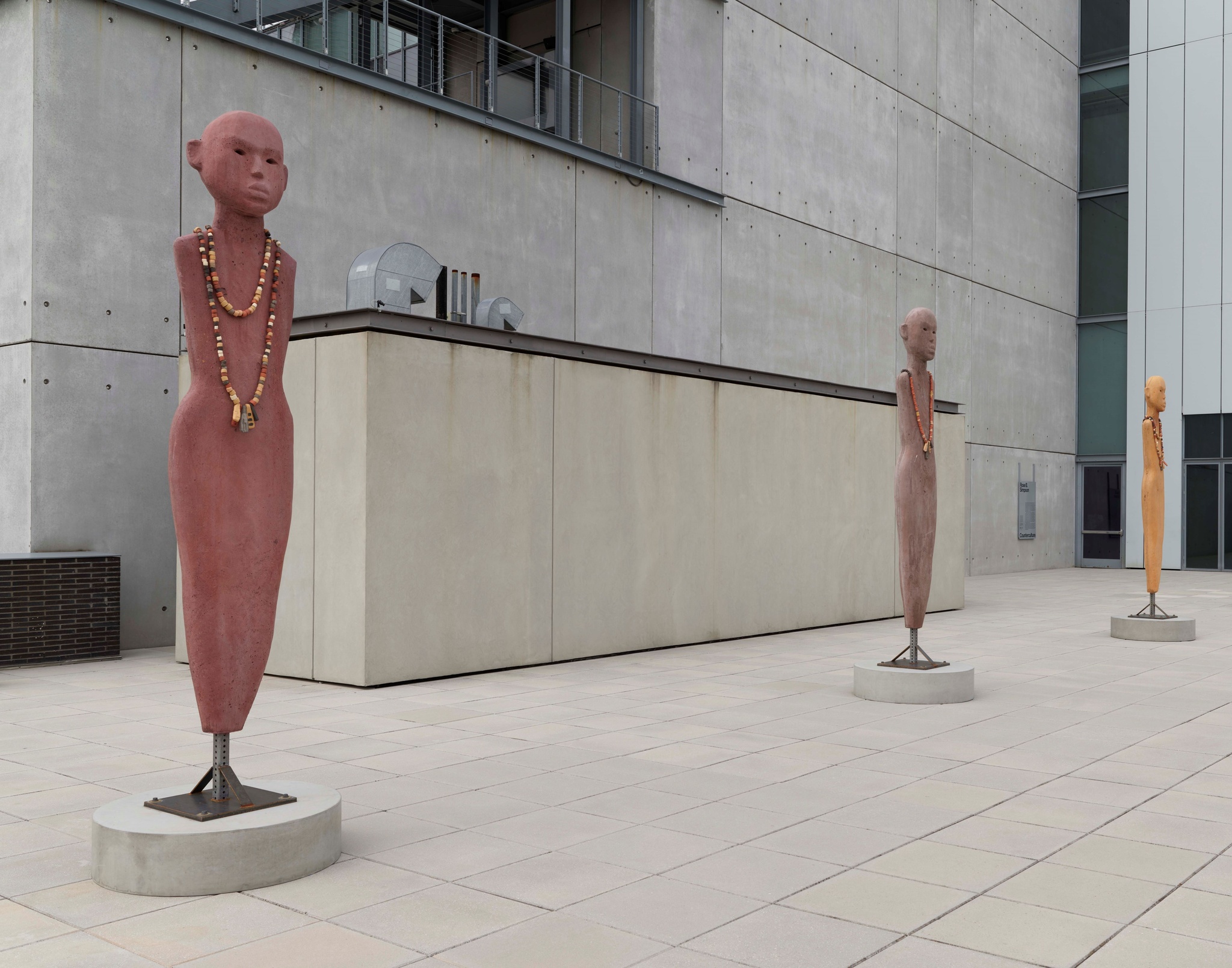 Five sculptures of smooth human figures with no limbs in a range of earth tones.