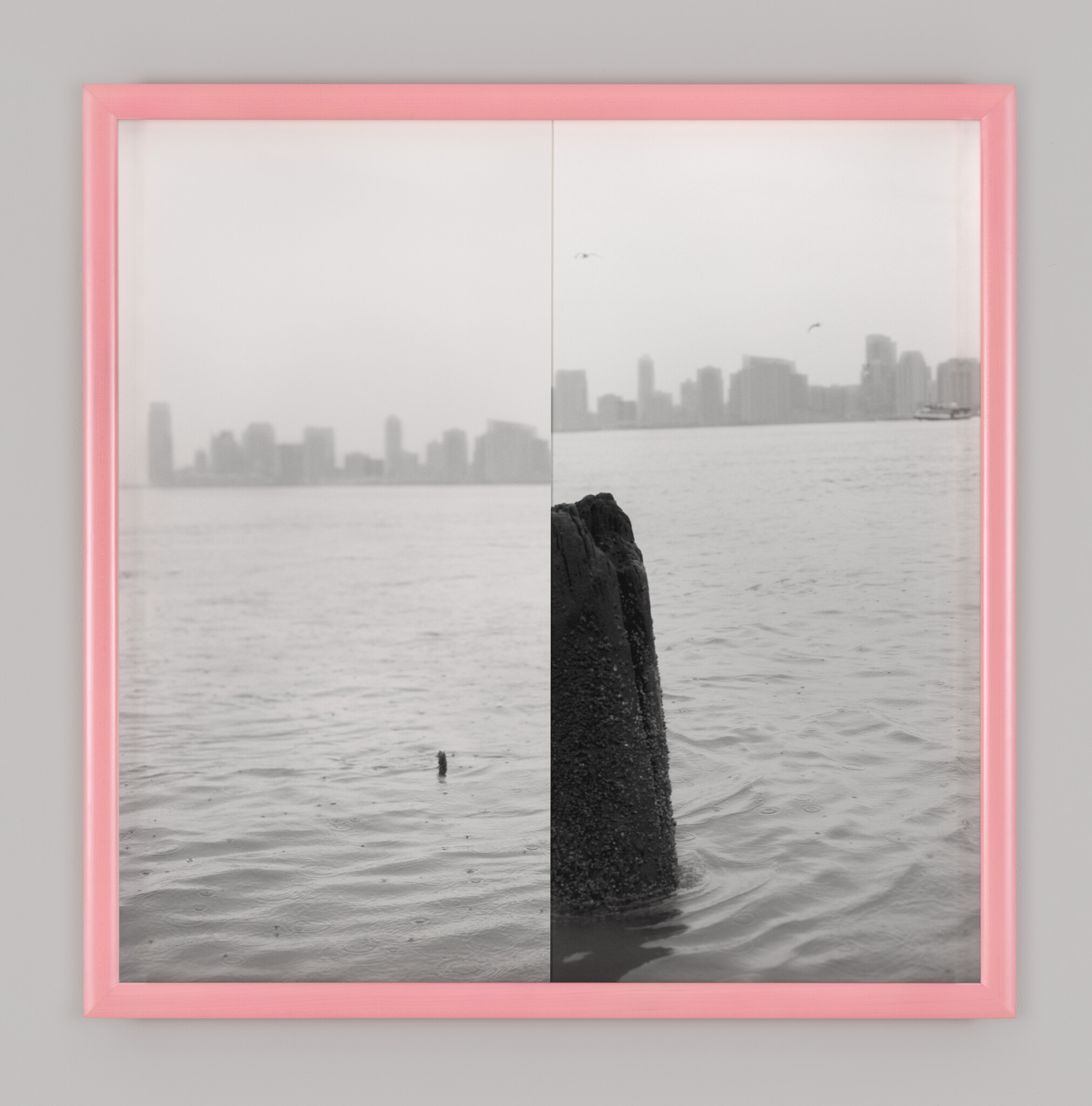 A framed black-and-white photo shows a wooden piling in water with distant city skyline.