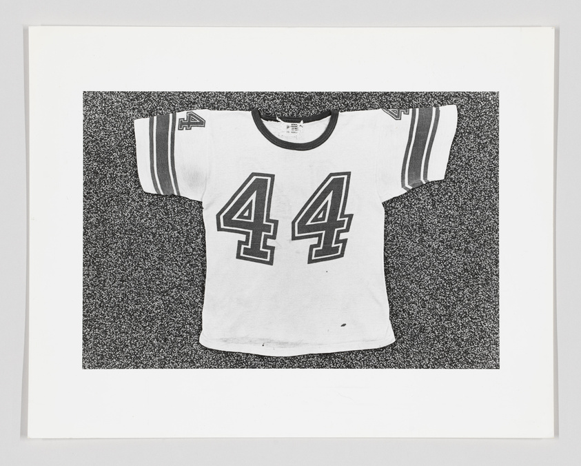 Black and white photo of a vintage sports jersey with the number 44, displayed against a textured background.