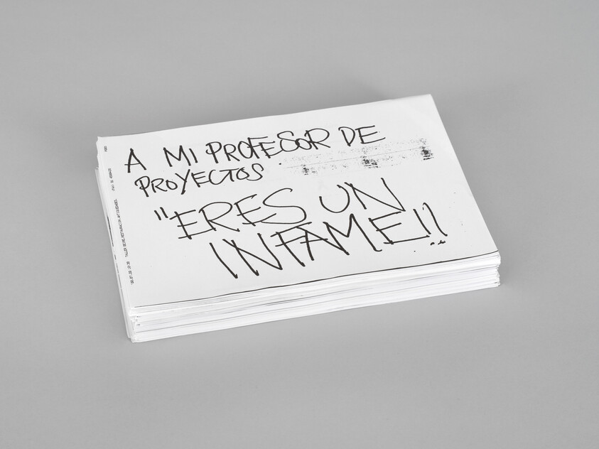 A stack of papers with handwritten Spanish message saying "A mi profesor de proyectos 'Eres un infame!'".