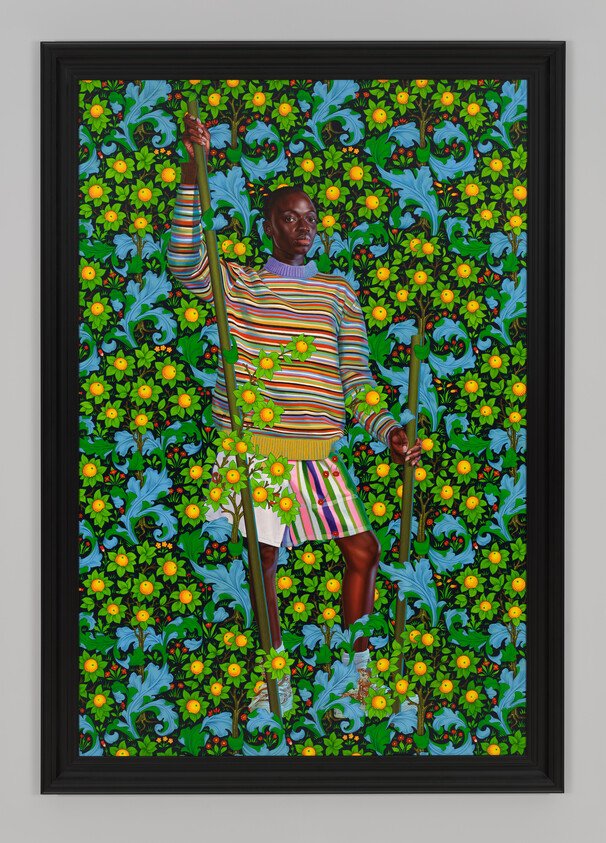 Person in colorful striped clothing stands against a vibrant floral background, holding a long stick.