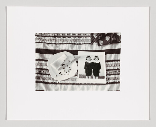 A patterned cloth holds a plate with a buttered roll and a book showing two girls.