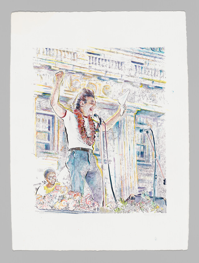 A speaker wearing a lei raises a fist and reads from a paper at a microphone.