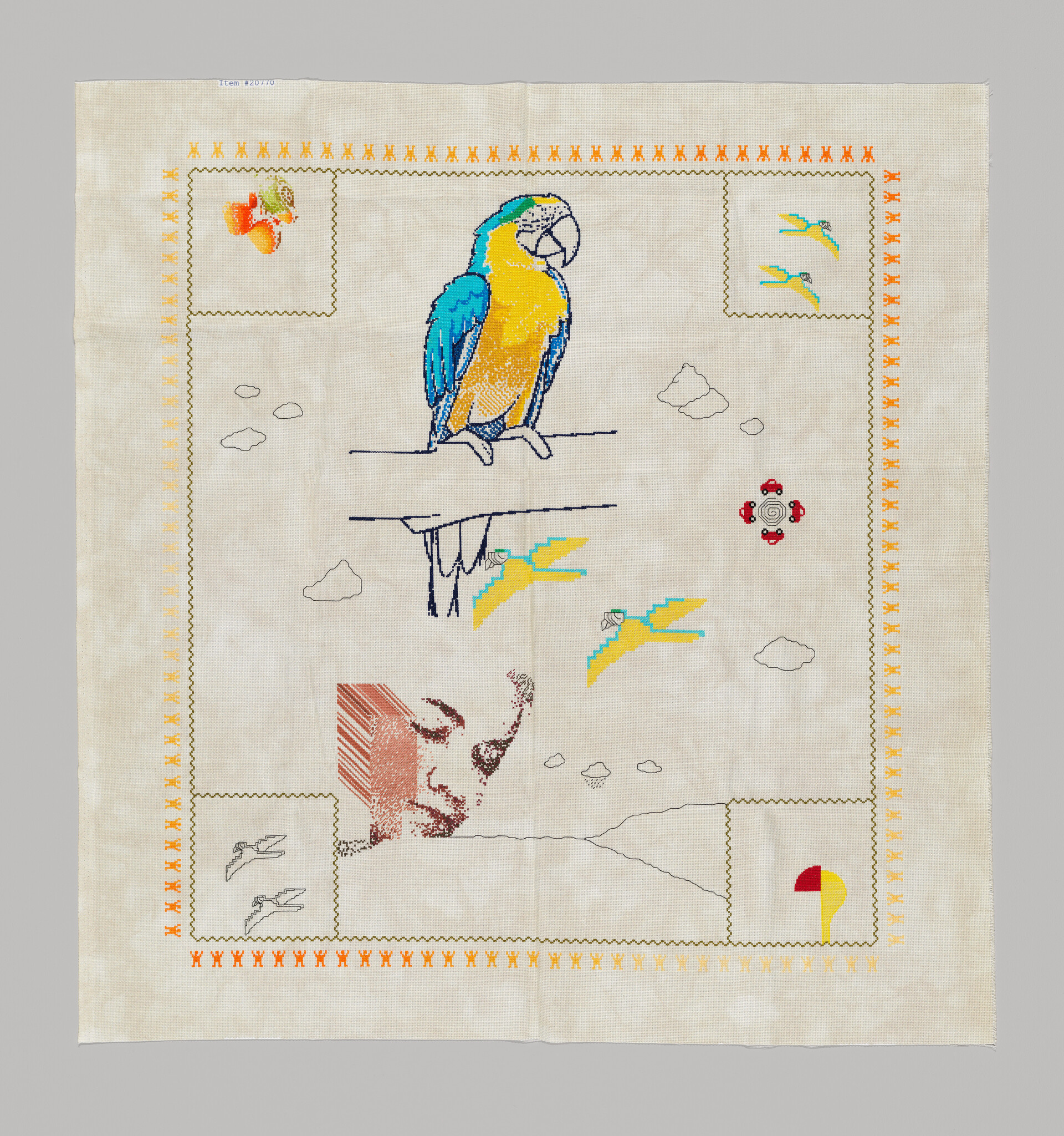 A blue-and-yellow parrot stitched on a decorative embroidered cloth with smaller bird motifs.