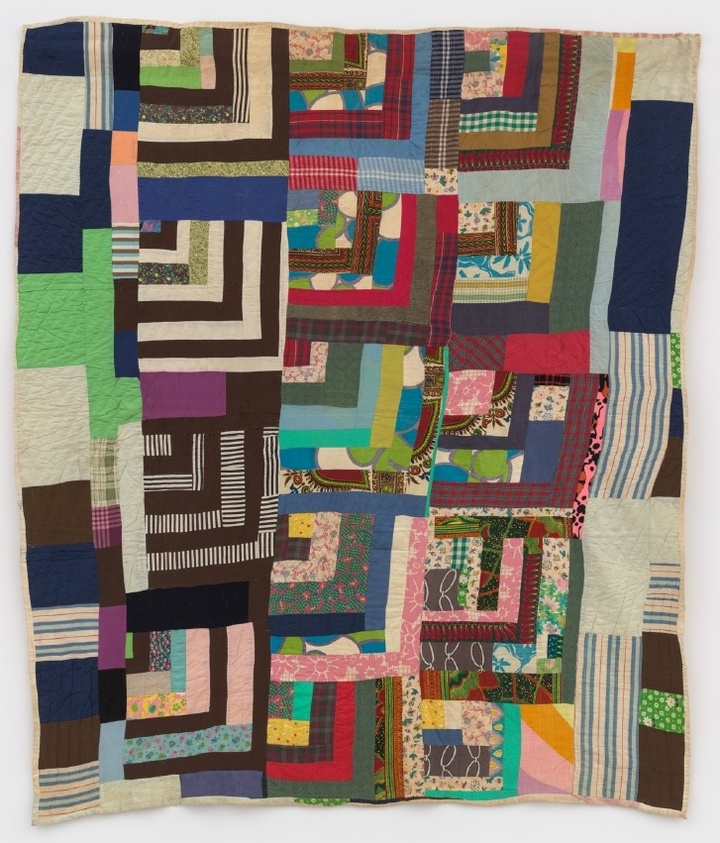 A colorful patchwork quilt with various geometric patterns and stripes in shades of blue, green, pink, and brown.