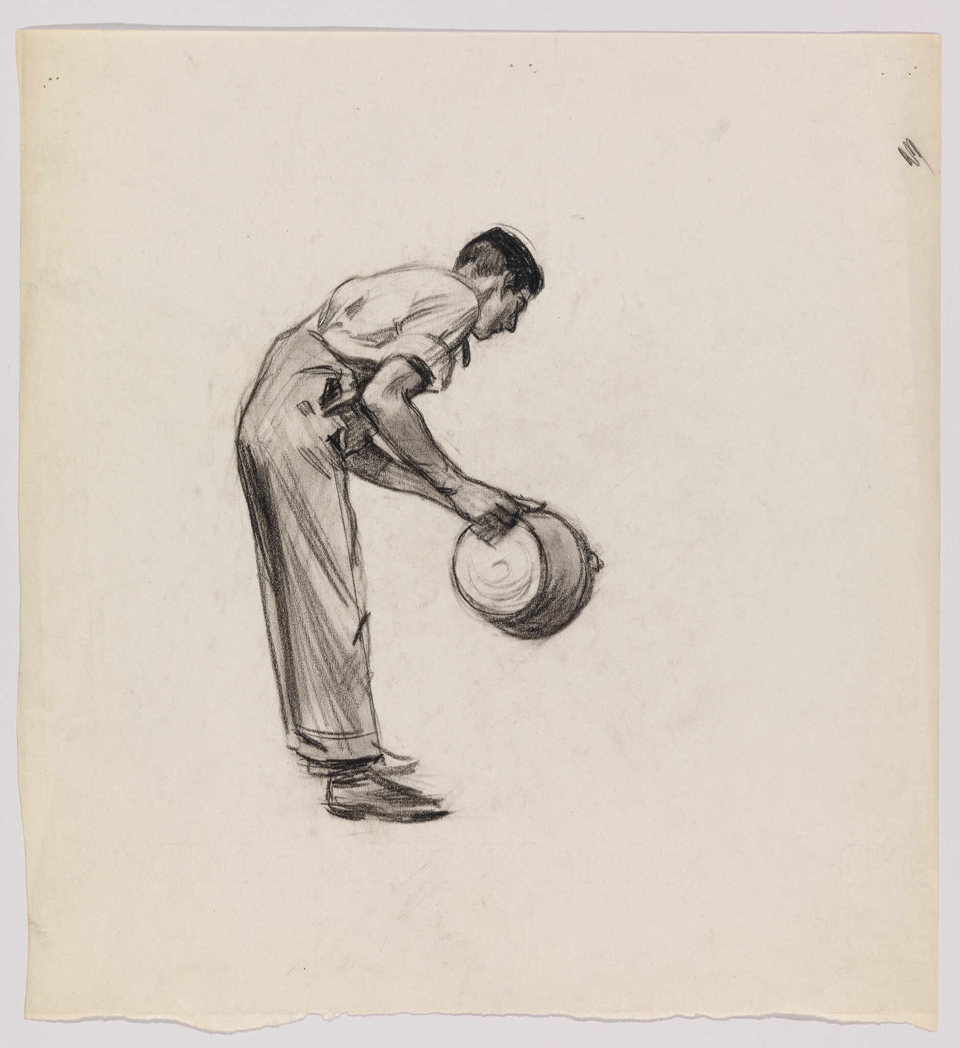 A man bends forward holding a hat in both hands at waist level.