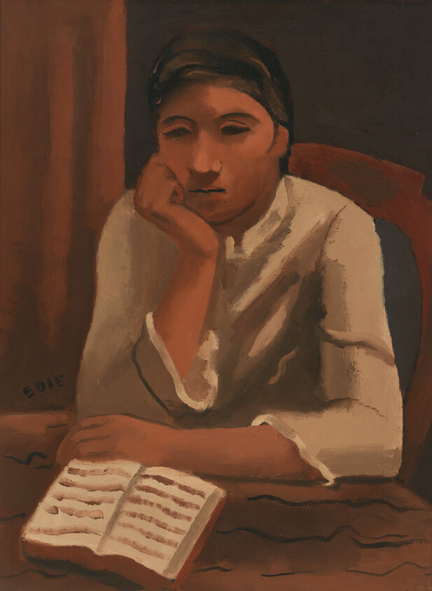 Young person resting chin on hand while looking at an open book on the table.