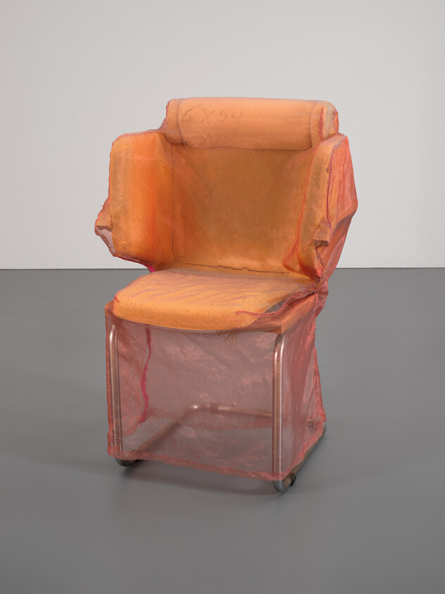 An orange padded chair wrapped in sheer pinkish fabric with metal frame and small caster wheels.