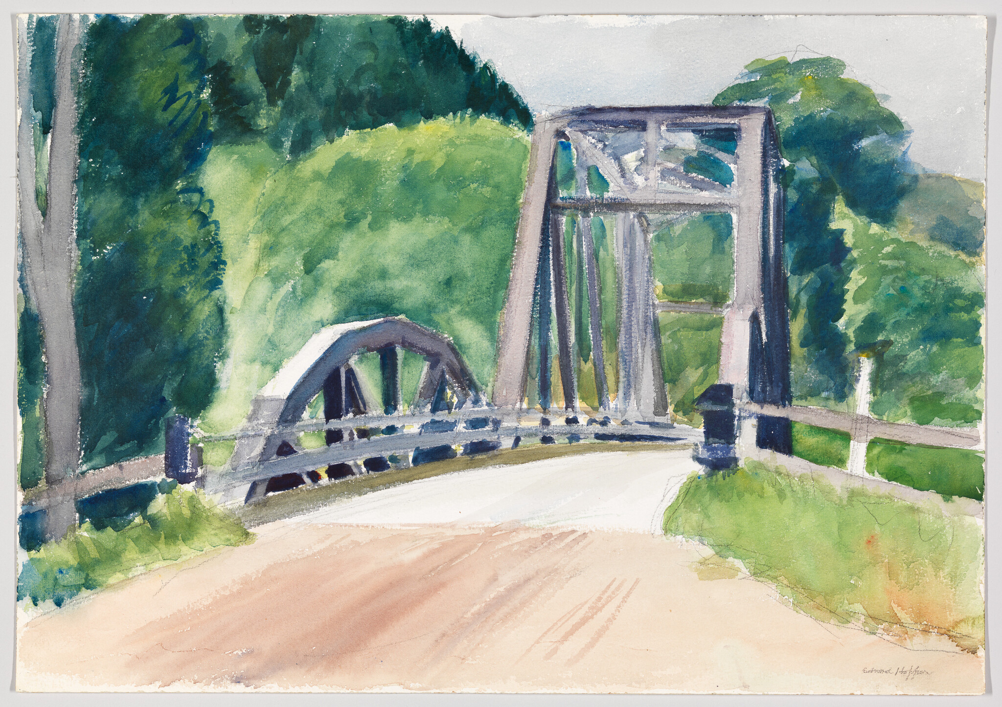 A small metal truss bridge crosses a country road surrounded by green trees.