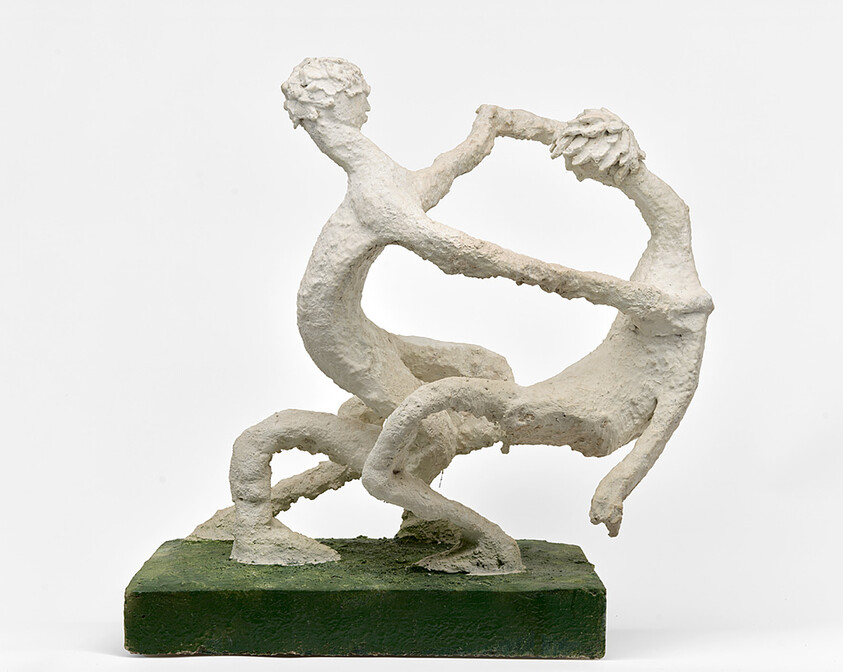 Two abstract white figures hold hands and dance in a circular motion on a green base.