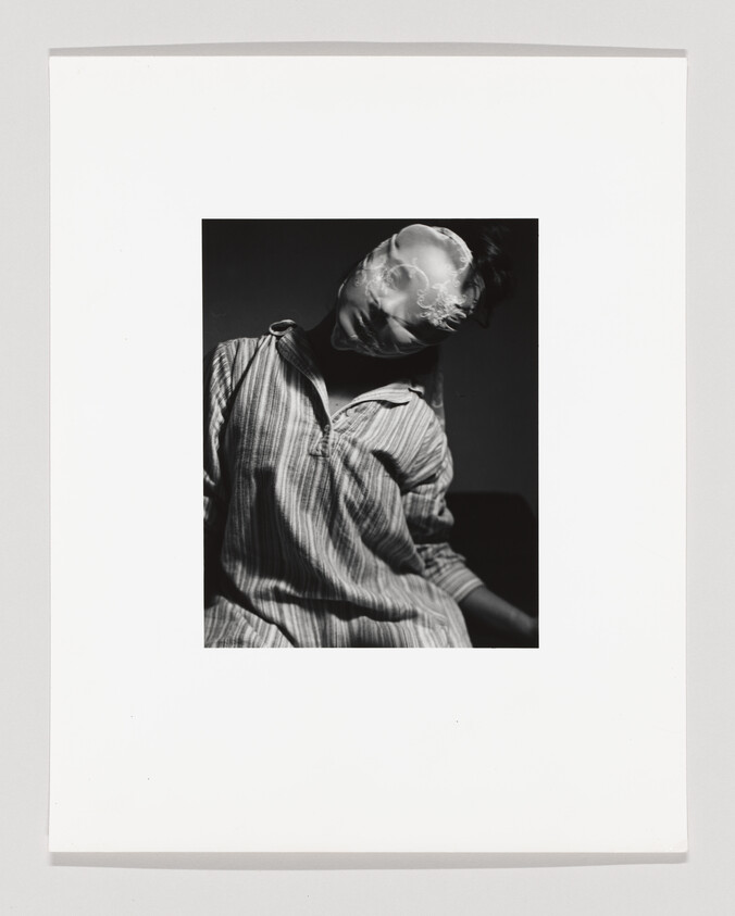 Person in a striped shirt with translucent fabric covering their head, leaning forward.