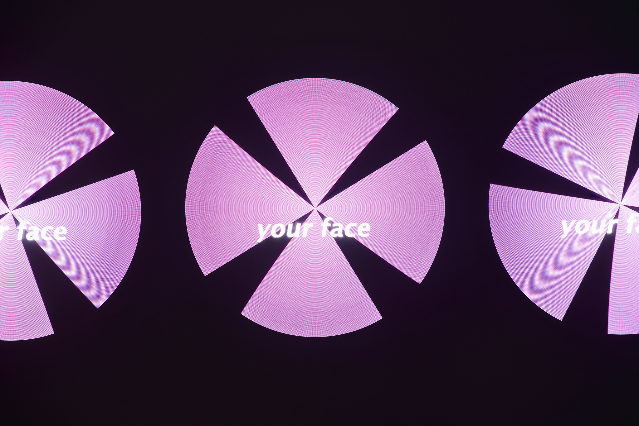 Three pink segmented circular lights display the words "your face" against a dark background.