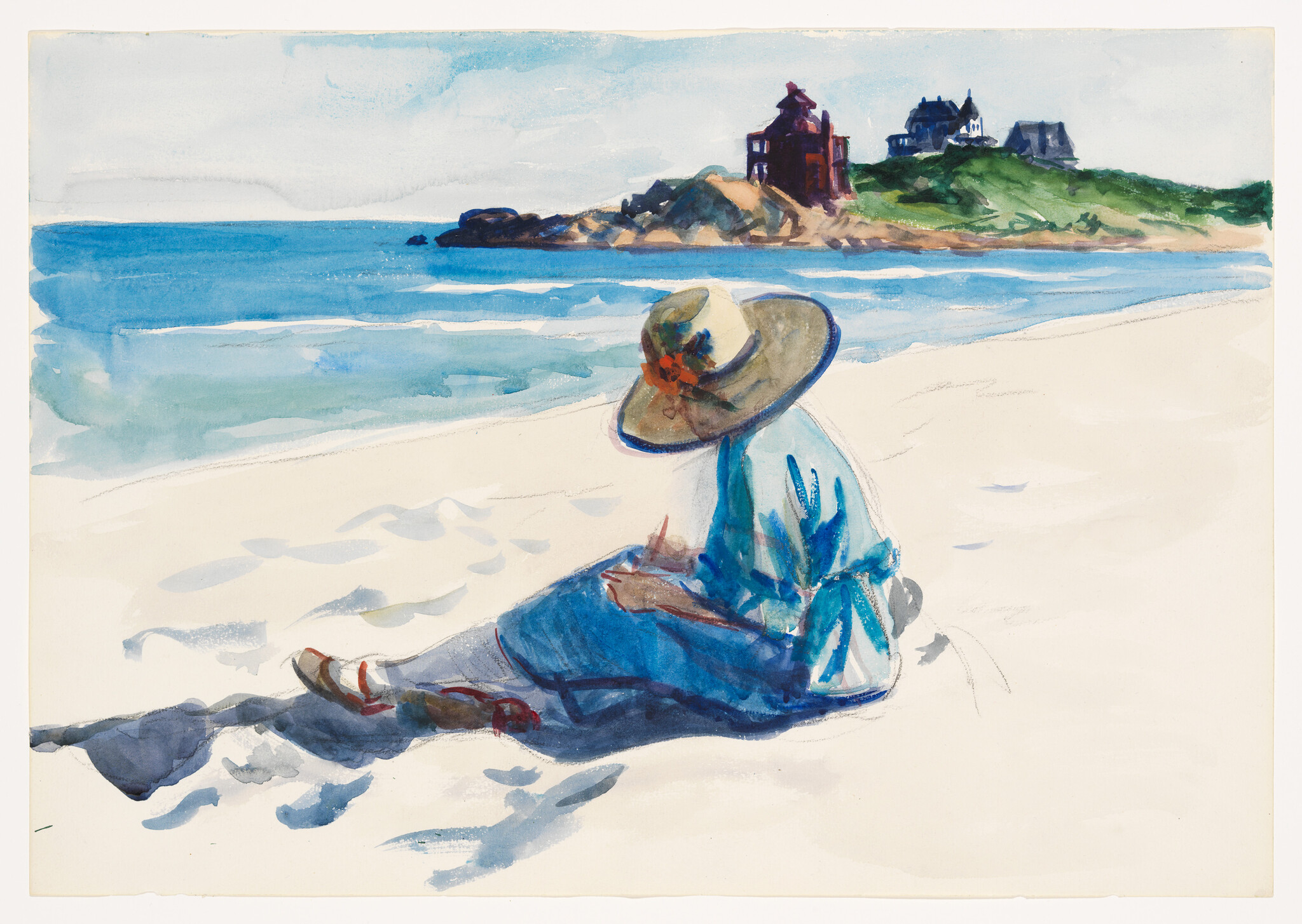 A person in a wide-brimmed hat sits on a sunlit beach looking toward coastal houses.
