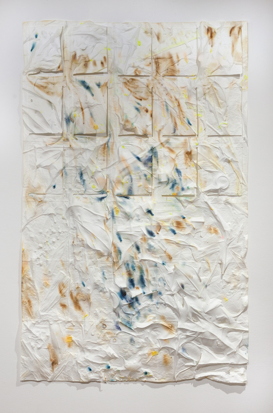 Crumpled white paper with abstract splashes of blue, brown, and yellow paint, creating a textured, artistic pattern.