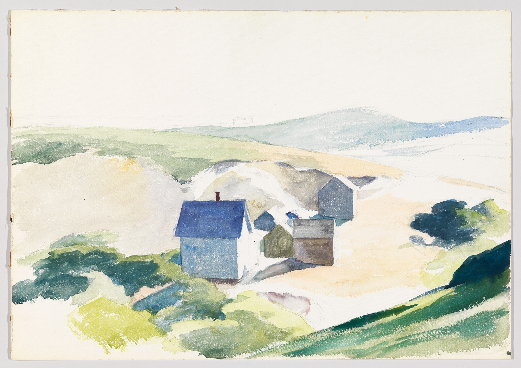 A small cluster of simple houses with blue roofs sits among sandy dunes and green hills.