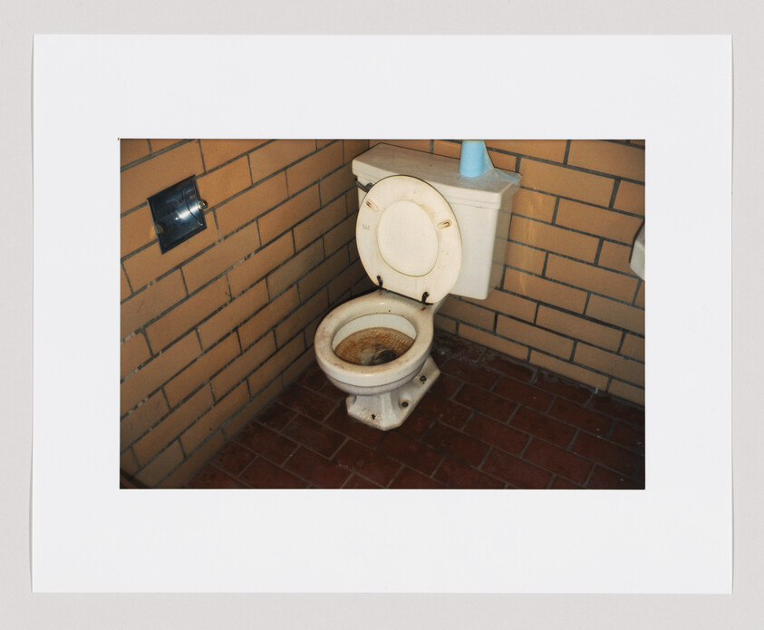 Old toilet with heavy rust and stains in a tiled corner restroom.
