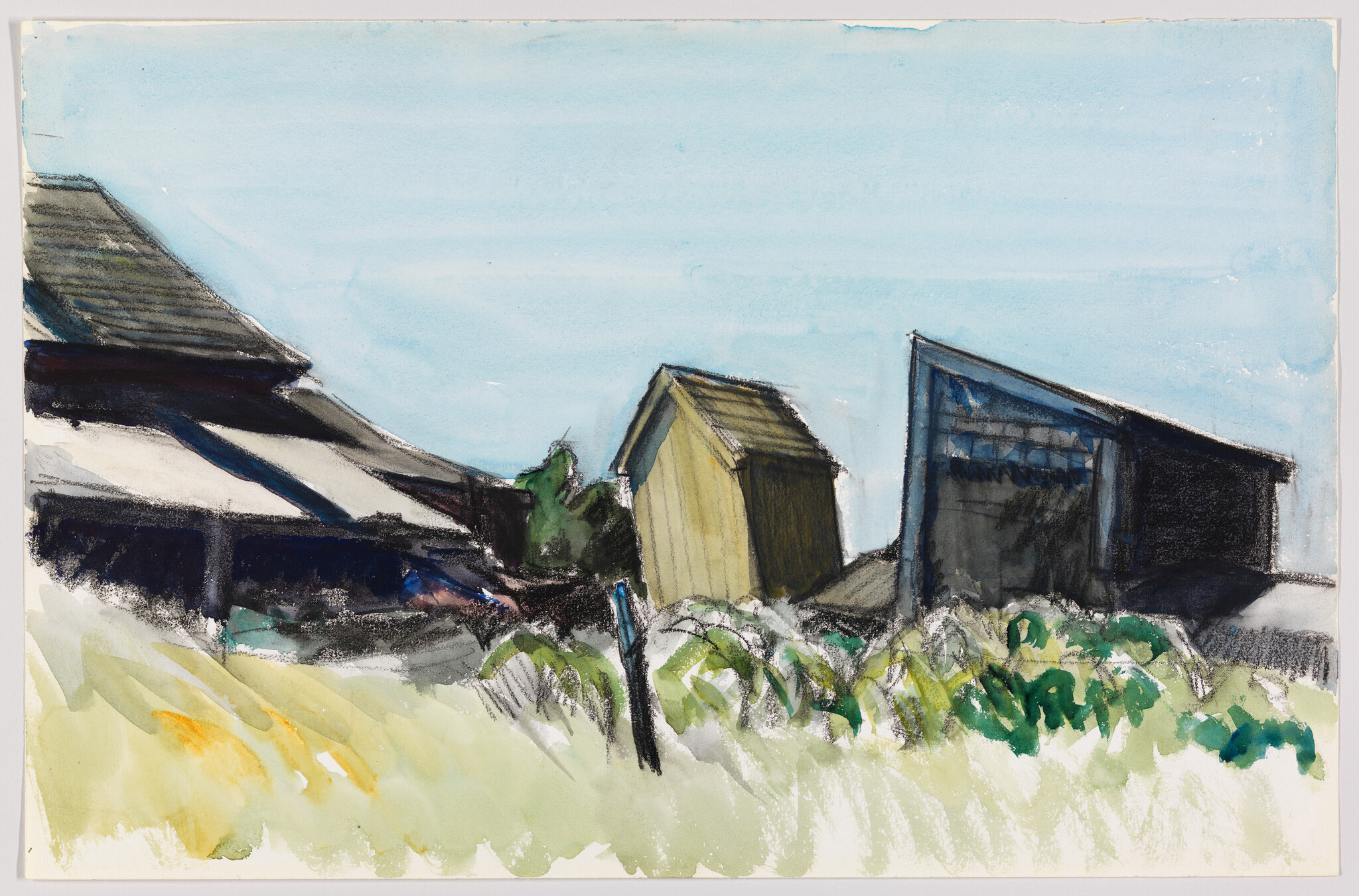 Three weathered beach huts and sheds sit among grasses under a clear blue sky.