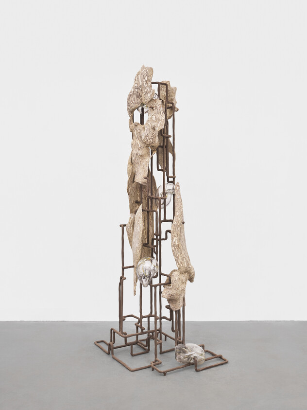 Tall metal-frame sculpture with weathered wood pieces and glassy forms arranged vertically.