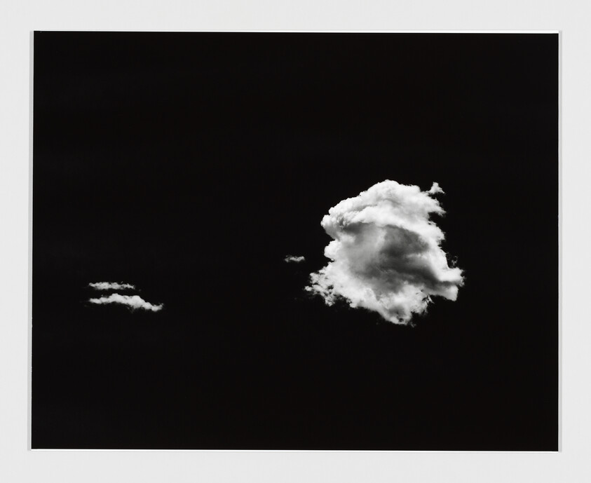 Two white clouds float against a dark sky, one large and one small.