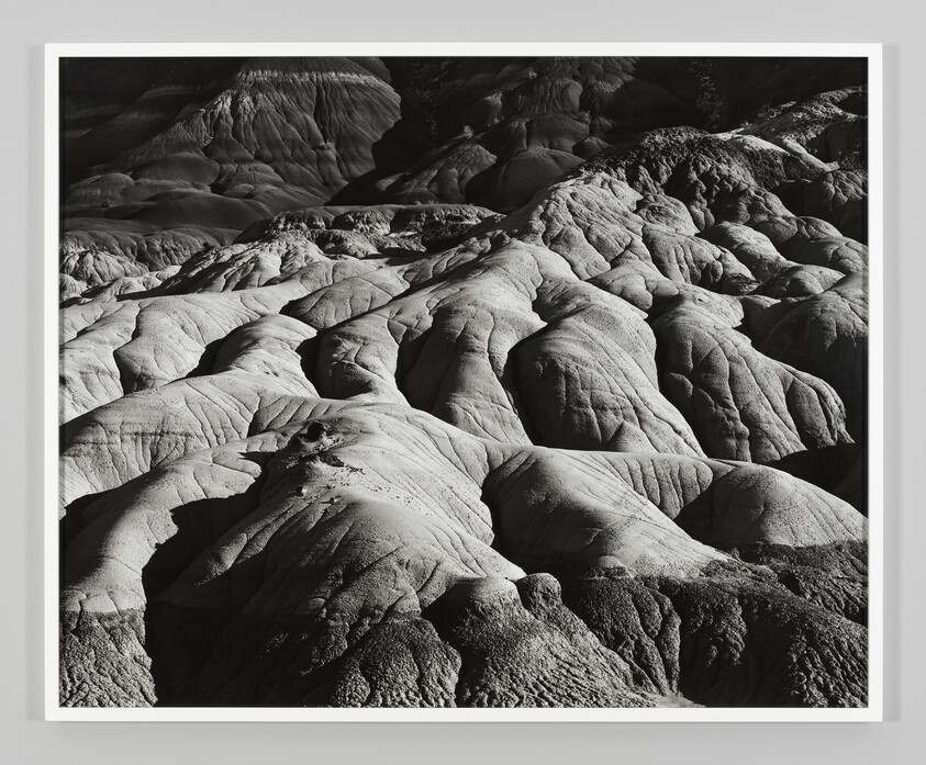 Rounded eroded rock formations with deep shadows creating ridged, layered textures across the landscape.
