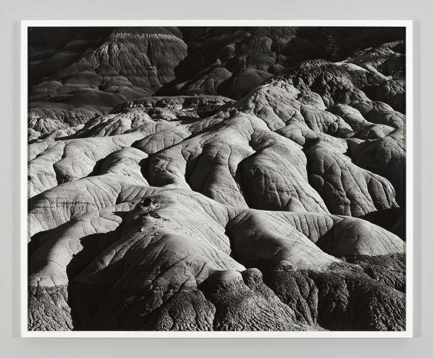 Rounded eroded rock formations and gullies creating wavy patterns across a stark landscape.