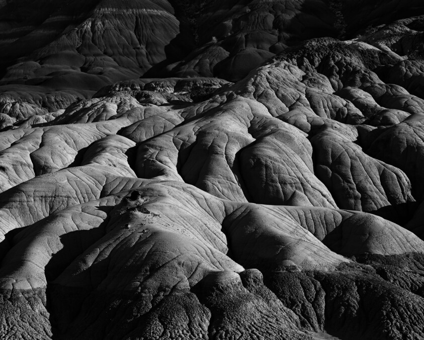Rounded eroded rock formations with deep shadows creating ridged, layered textures across the landscape.