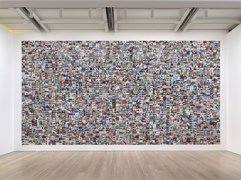 Large wall covered with hundreds of small, colorful photographs in a gallery setting.