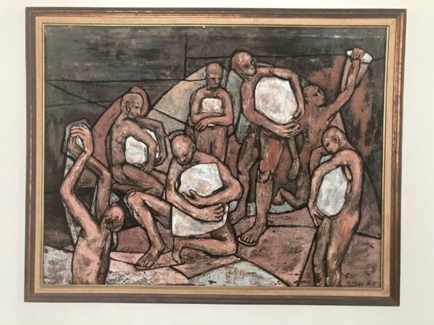 Several abstract human figures hold large white stones, standing and kneeling together in a group against a dark background.
