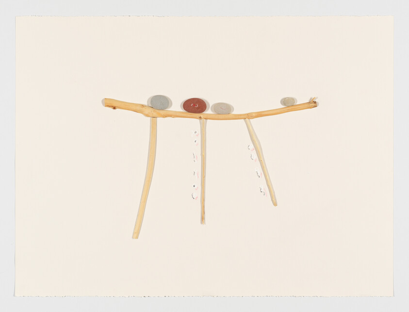 A simple three-legged wooden stand with four round stones balanced along its top.