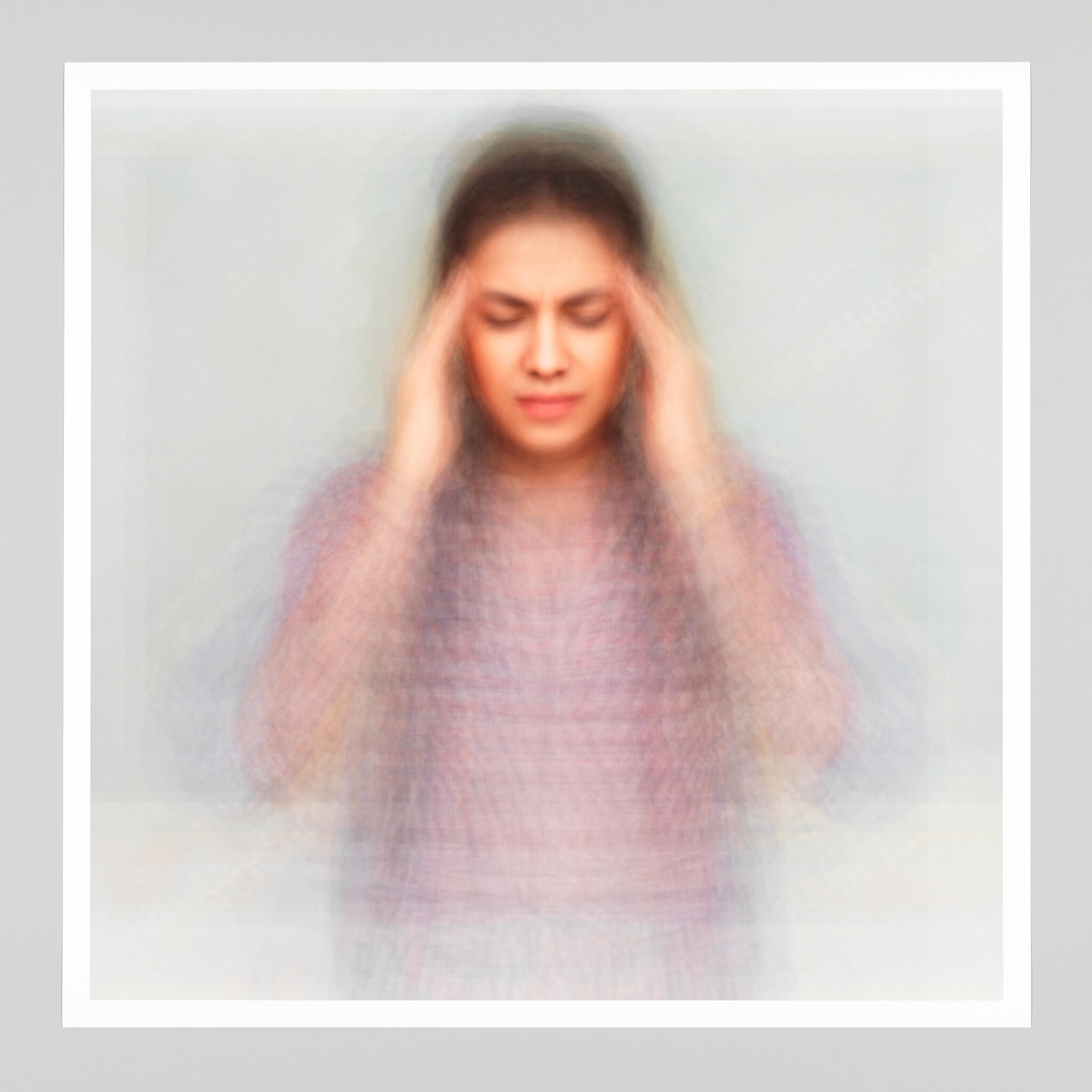 A young woman presses her temples with closed eyes, appearing to have a painful headache.