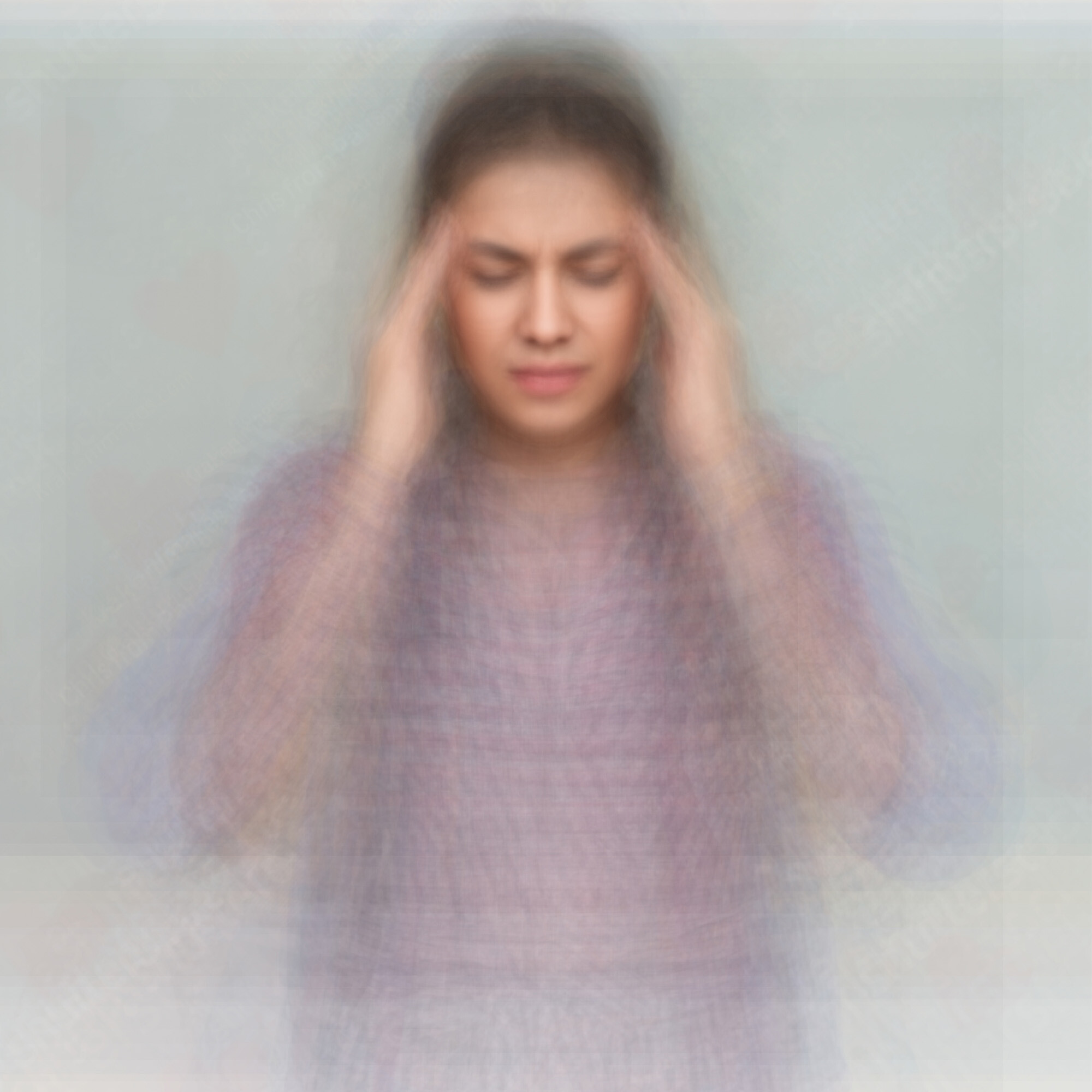 A woman with eyes closed pressing her temples, appearing to have a headache or stress.