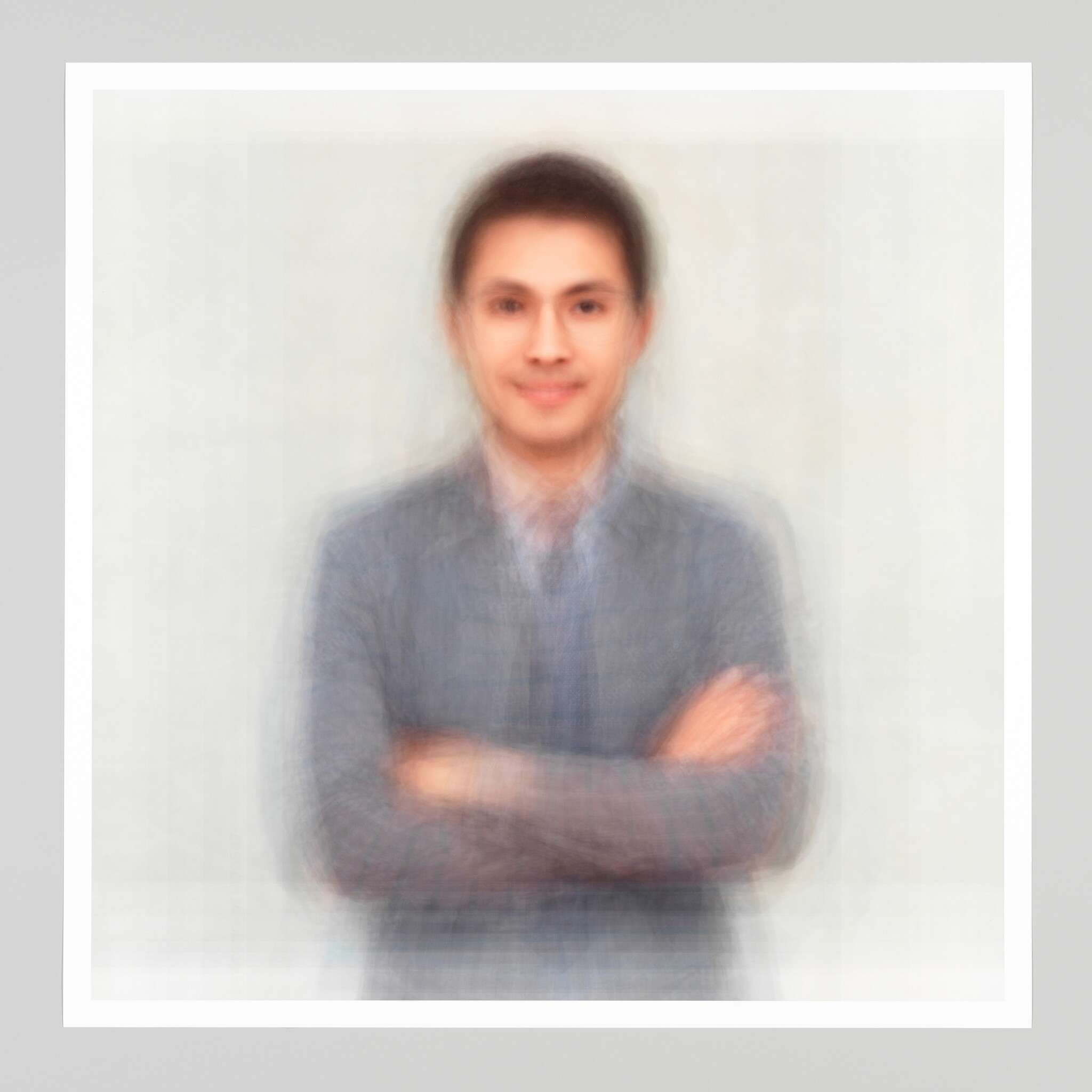 A smiling man in a blazer stands facing the camera with his arms crossed.