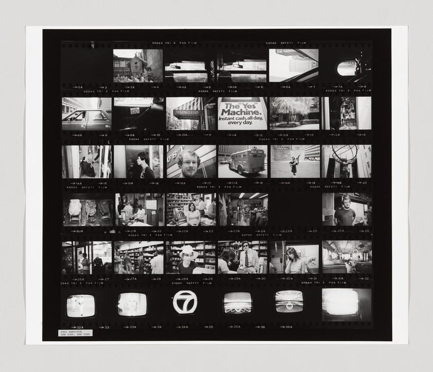 Contact sheet of black-and-white photo negatives showing varied street and portrait scenes, including a "The Yes Machine" sign.