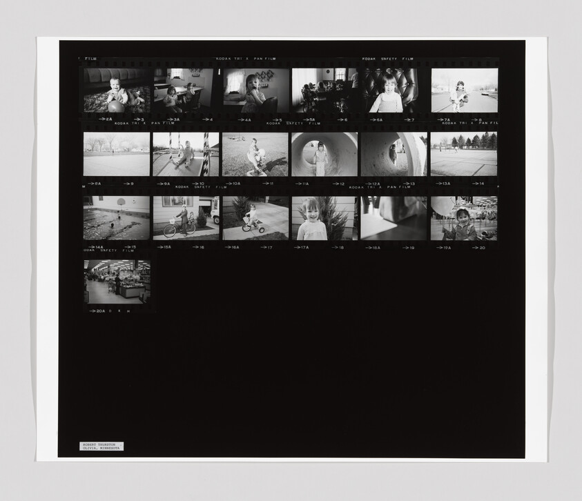 Black-and-white contact sheet showing multiple small family photos of children playing, riding bikes, and posing.