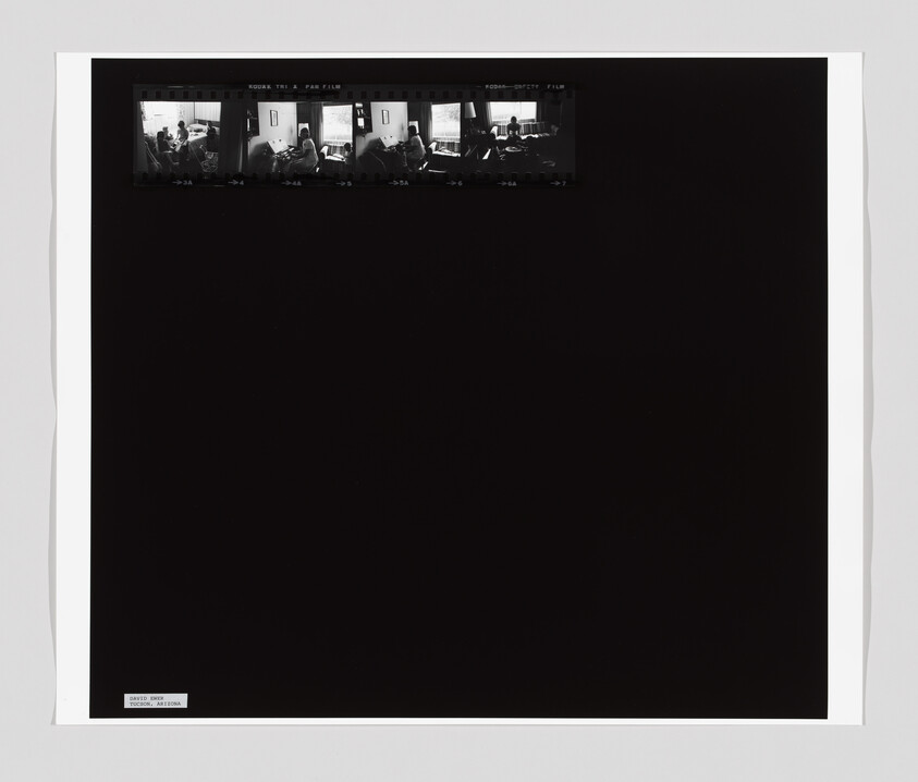 Three small black-and-white film frames show people sitting and talking around a table near a window.