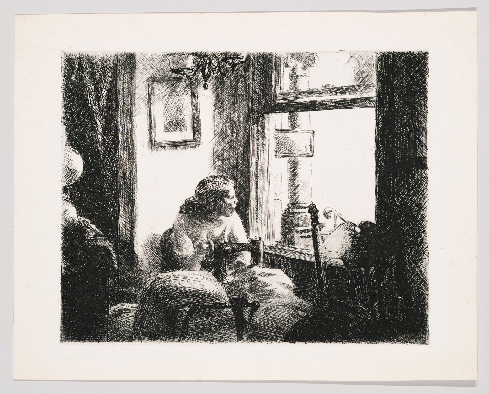 A woman at a sewing machine looks thoughtfully out a bright window.