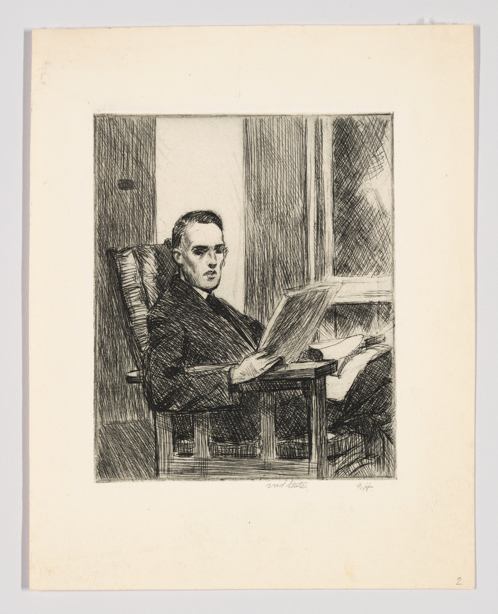 A man sits in an armchair near a window reading a newspaper.