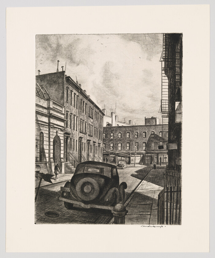 A vintage car parked on a quiet city street lined with brick rowhouses and fire escapes.