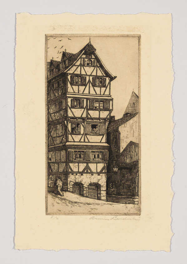 Tall timber-framed medieval house rising above a narrow street with a person walking nearby.