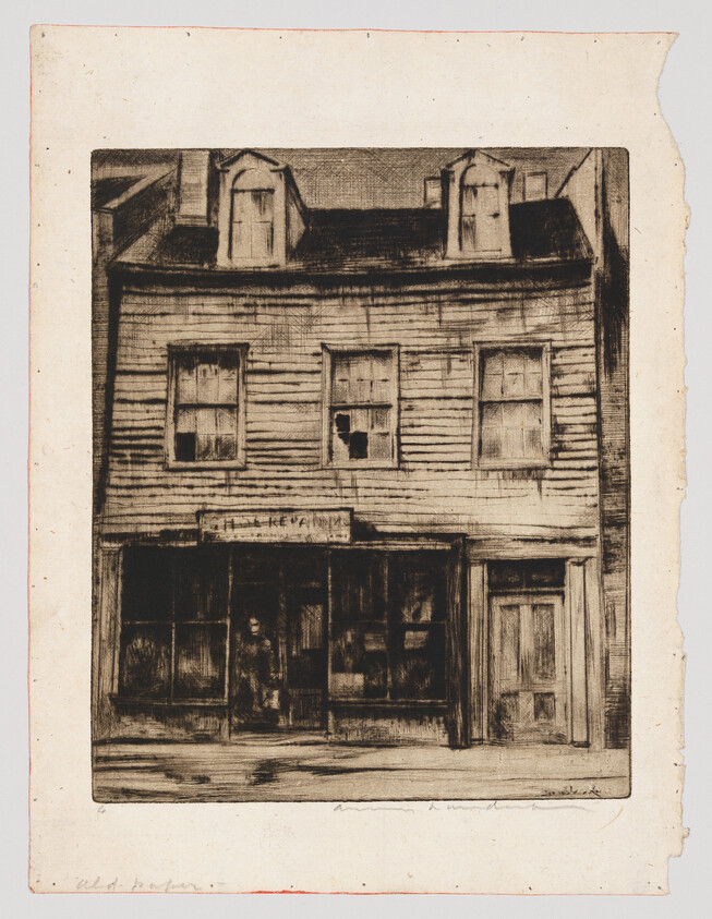 Old two-story wooden storefront with display windows and a person standing in the doorway.