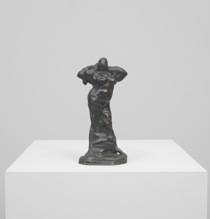 Small dark bronze sculpture of a standing woman with hands raised to her head on a pedestal.
