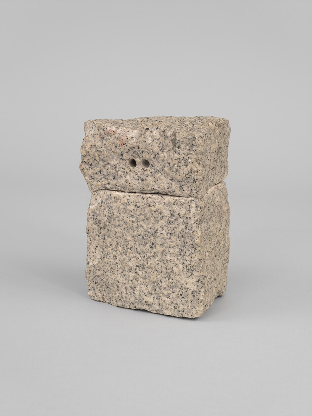 Two rough granite blocks stacked vertically, top block showing two small drilled holes.