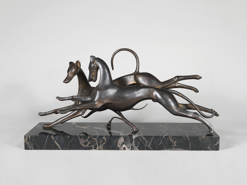 Three bronze greyhounds leap in unison on a rectangular dark marble base.