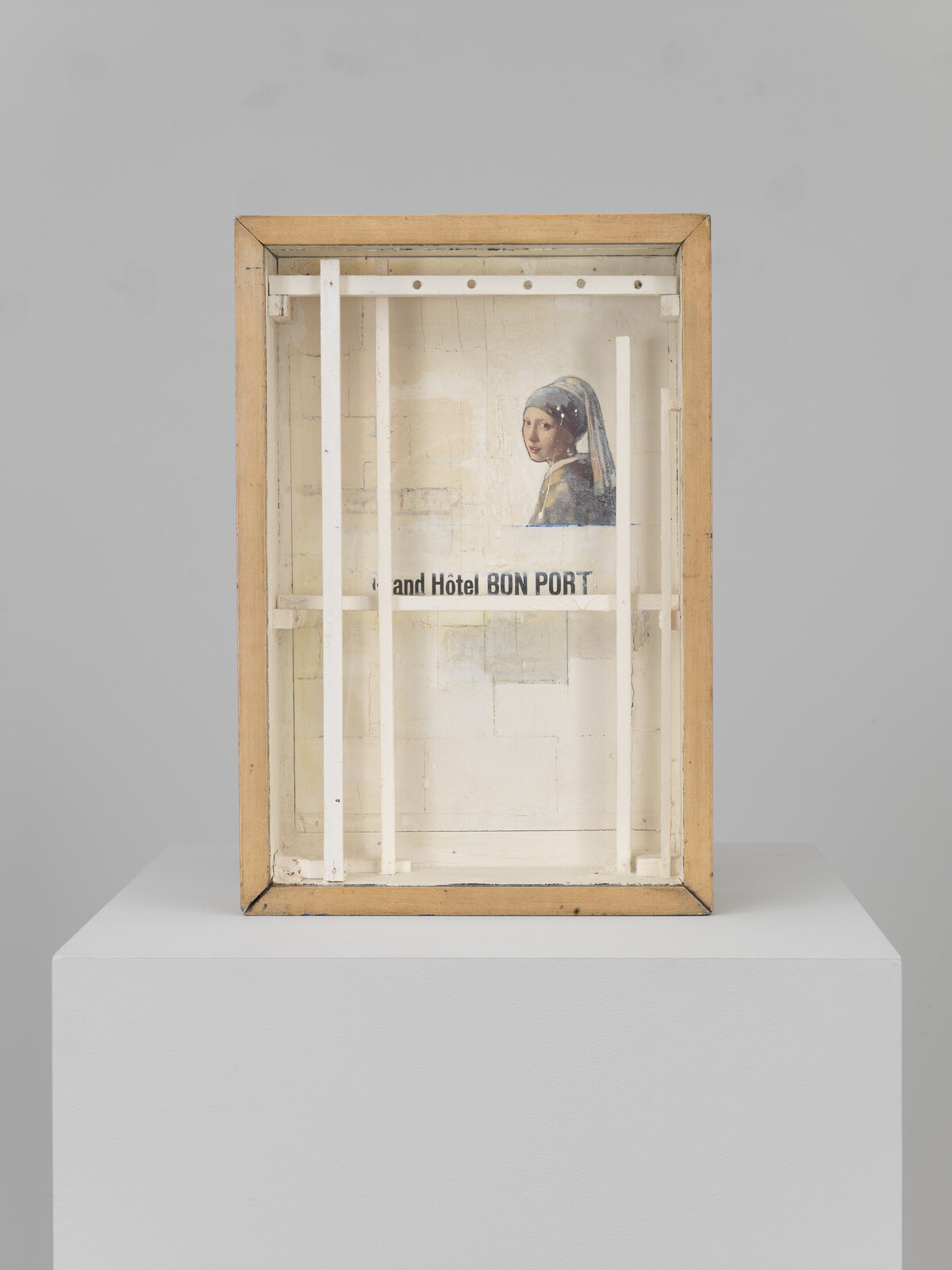 A wooden display box with vertical white bars containing a small girl with a pearl earring reproduction.