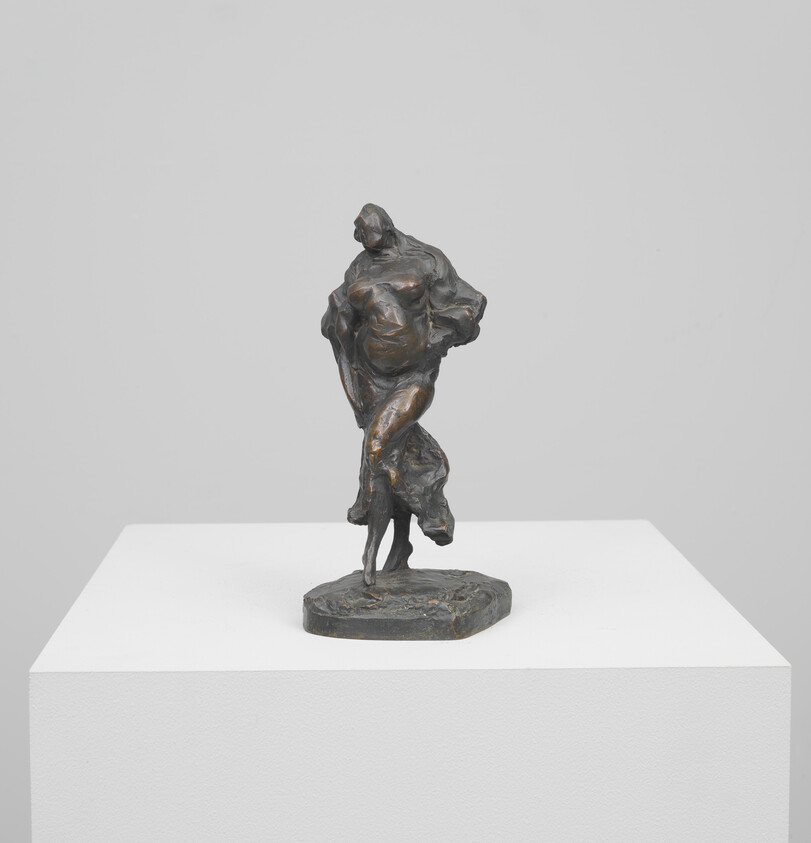 Bronze sculpture of a draped standing figure balancing on one foot on a pedestal.