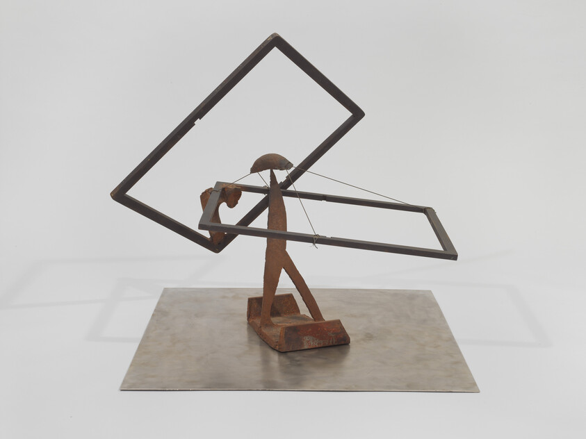 A rusted metal figure balances two tilted rectangular frames held together by thin wires.